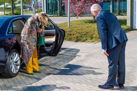 Máxima stapt uit auto. Heeft nog geen mondkapje op. Een man buigt voor haar